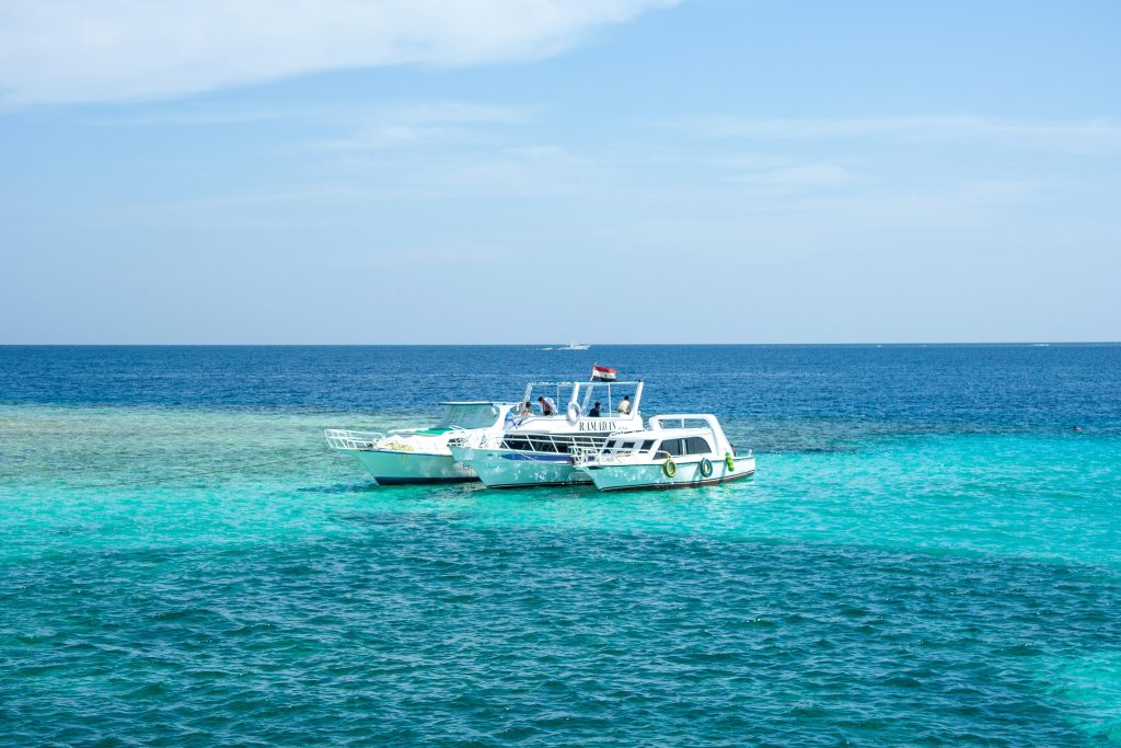 a white catamaran floating in the beach of tulum