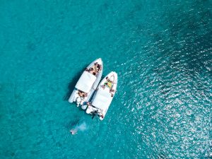 group of people relaxing on two connected boats in clear turquoise water during a private charter in Tulum