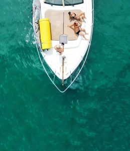 Friends relaxing on a boat in Tulum with turquoise water around them.